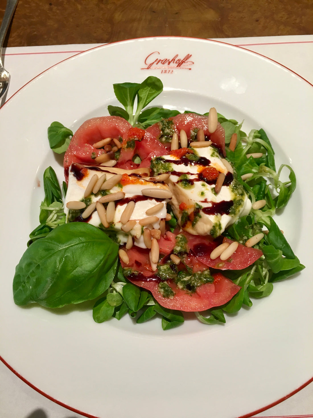 Teller mit Tomaten, Burrata und gerösteten Pinienkernen