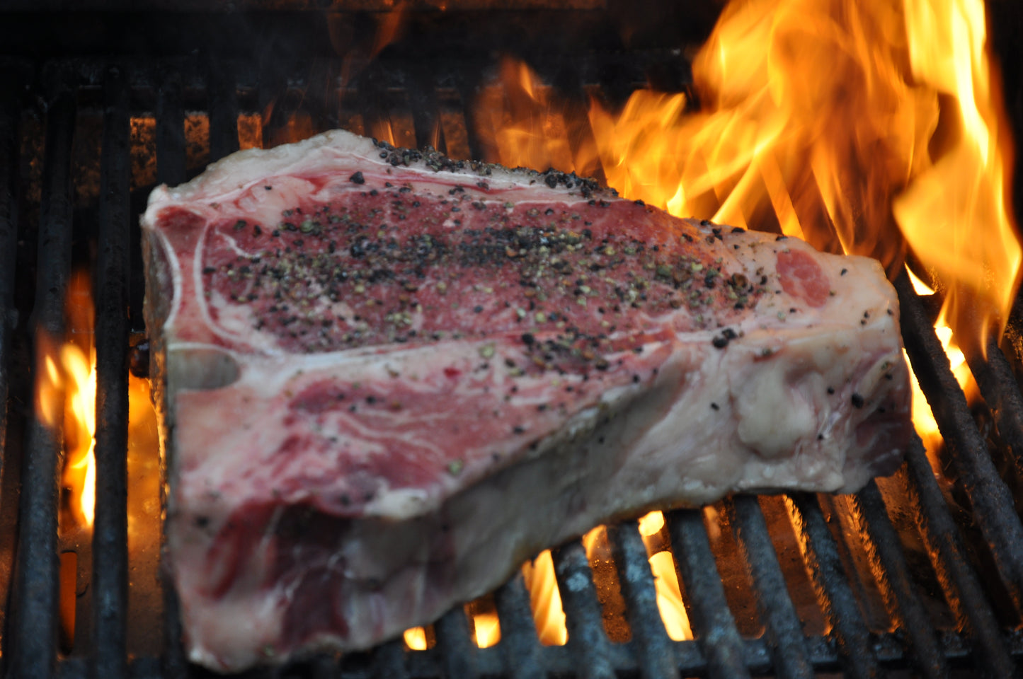 Ein T-Bone Steak auf dem Grill im Feuer